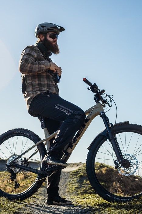 Billedet viser en mand der holder pause på sin e-mtb, mens han spiser en snack.