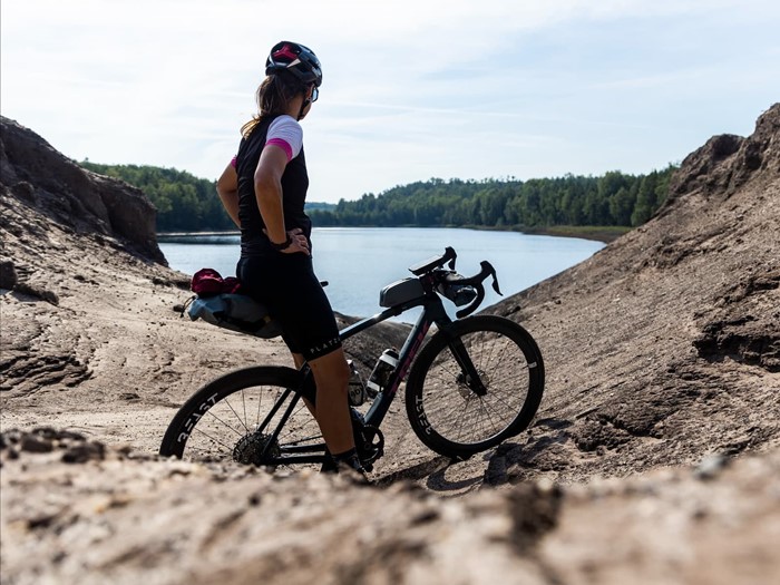 Billedet viser en kvinde på en gravel cykel der holder en kort pause mens hun nyder udsigten.